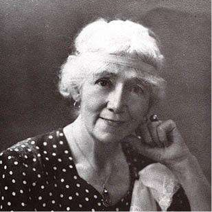 Black and white photo of a woman sitting and smiling at the camera