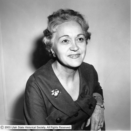 Black and white photo of a woman smiling and sitting on a chair